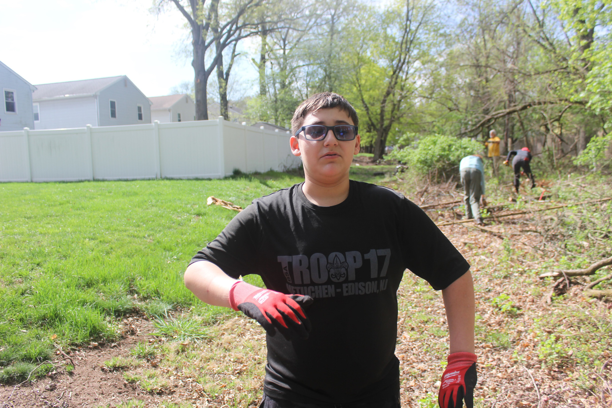 Scout wearing gloves and sunglasses standing in a grassy clearing.