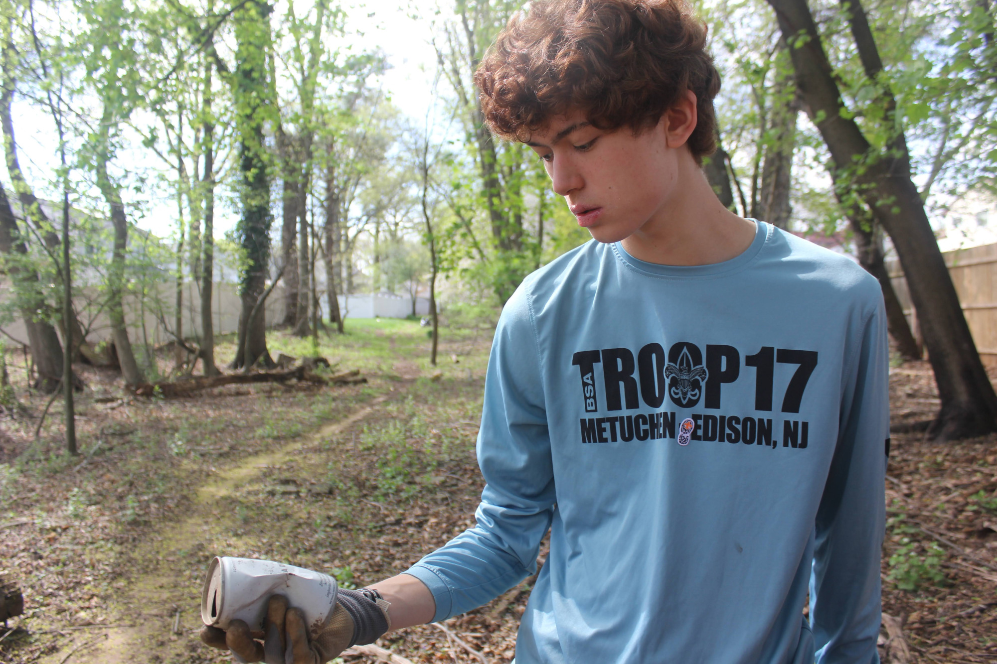 Scout examining a discarded item in a wooded area.