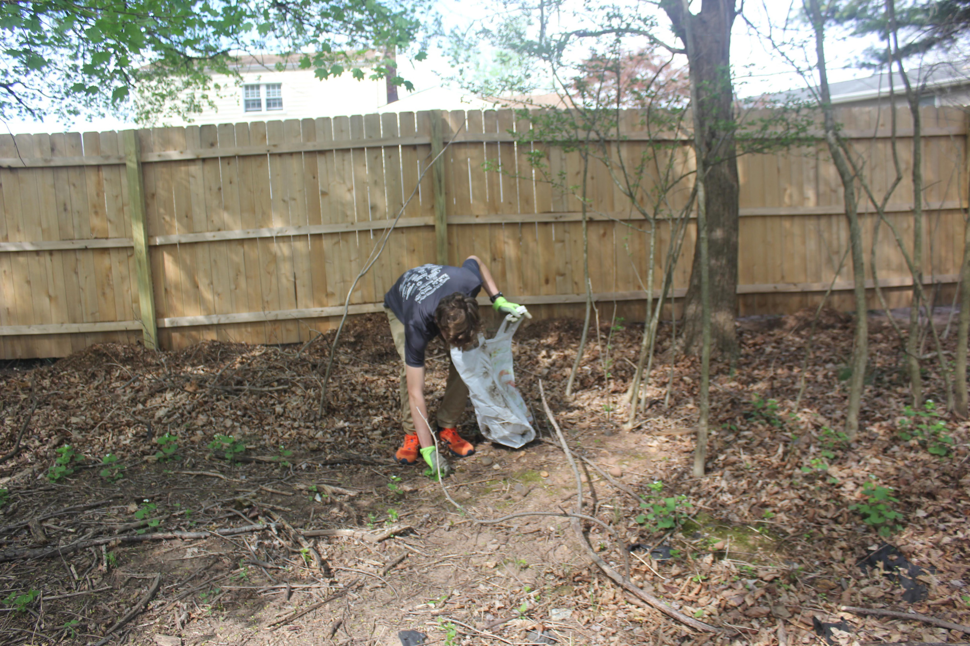 Scout lifting debris off the ground near a fence line.