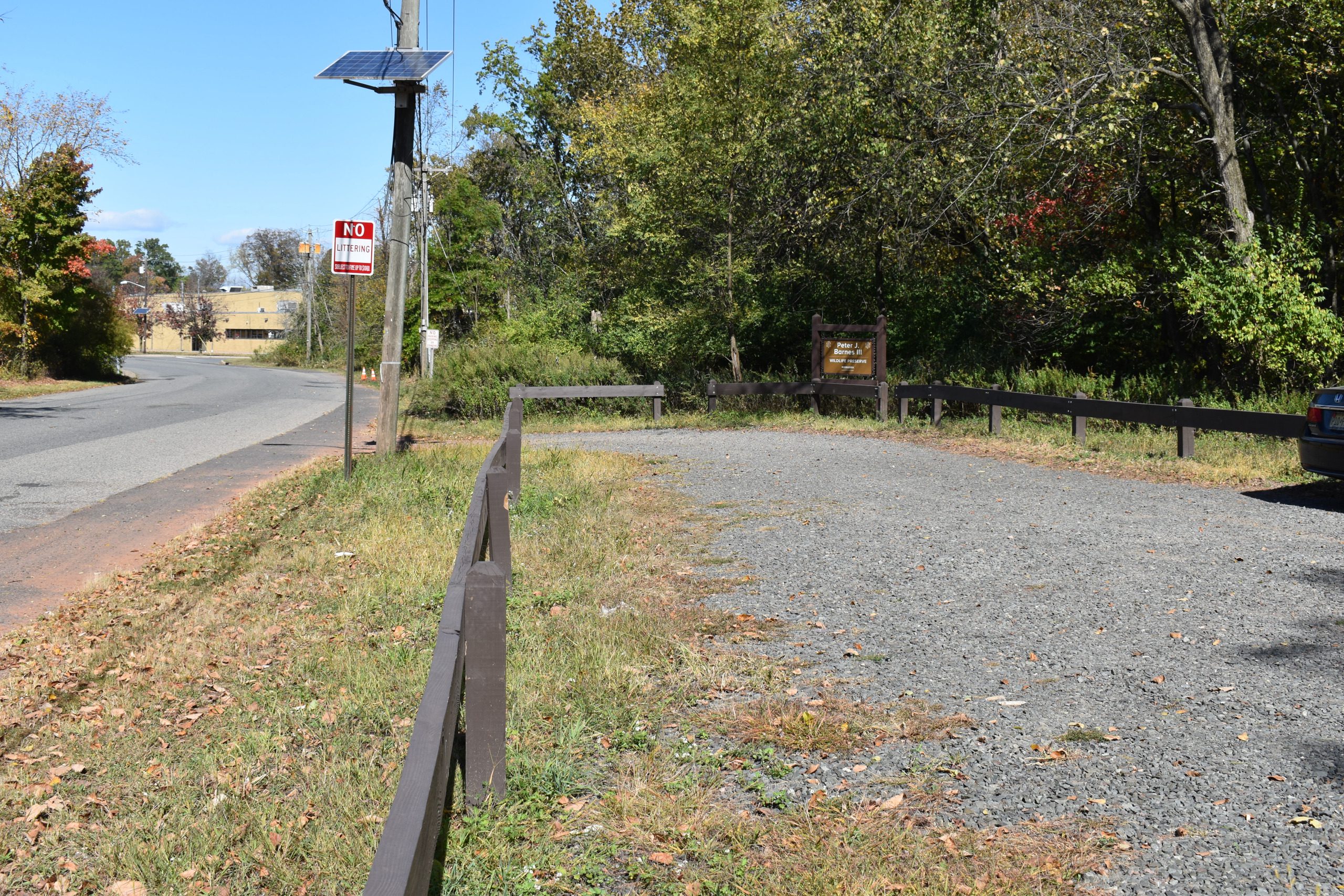 Small gravel parking area with trailhead access near a road.