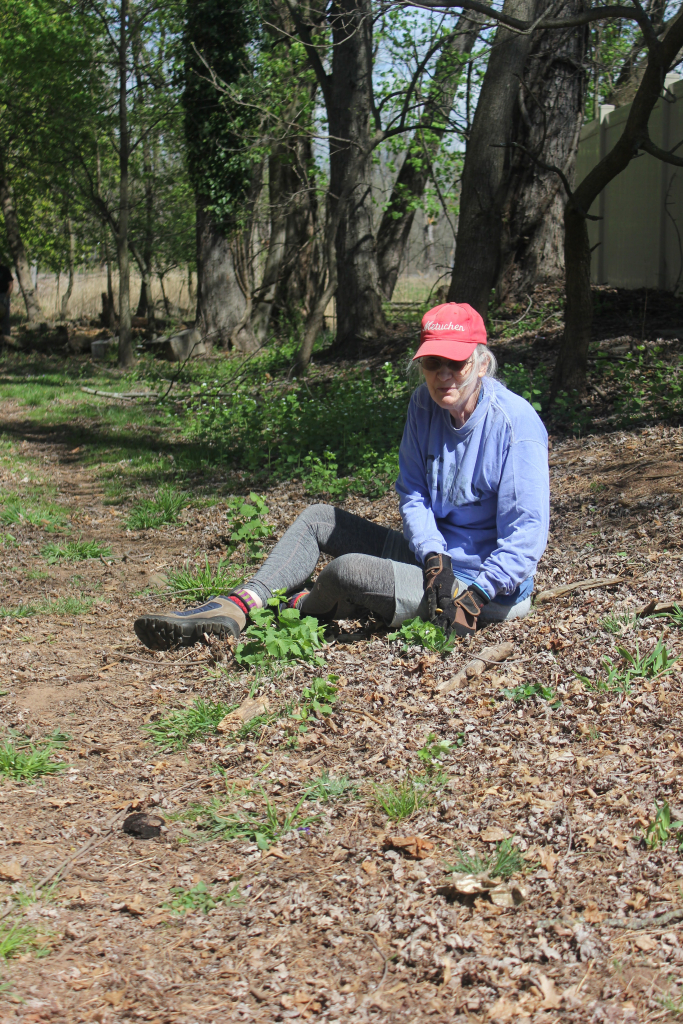 Volunteer sitting on the ground outdoors, resting with gloves on.