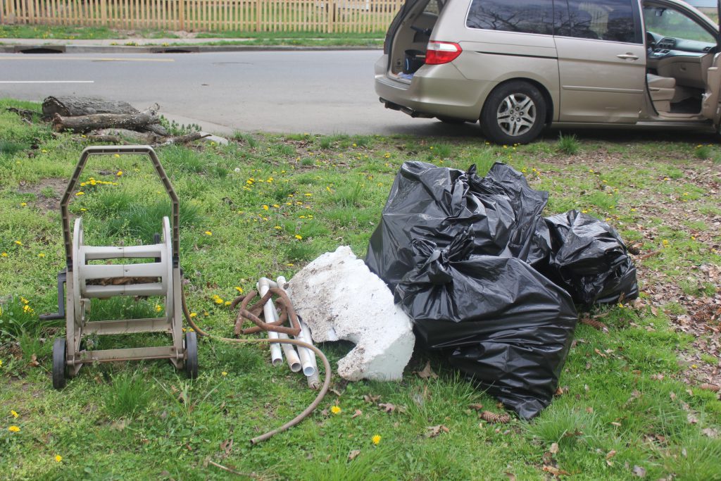 Pile of trash bags and debris near the curb beside a parked van.